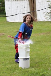 A child smashes a water balloon while galloping on a hobby horse