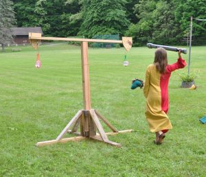 A youth aims for the quintain shield, which has a water balloon hanging from it instead of a bag of flour.