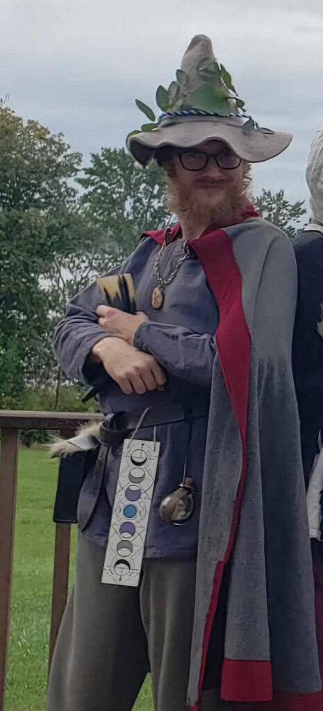 man wearing tall pointy hat, cloak, and tunic